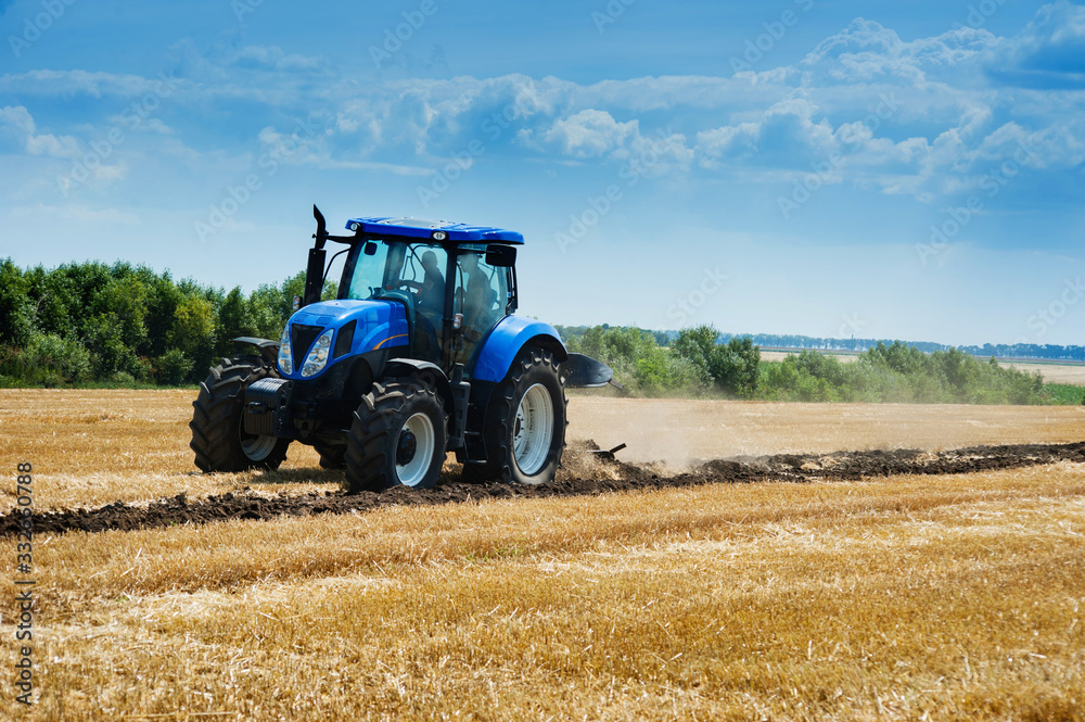 Obraz premium blue new tractor plowed soil on the edge of a field