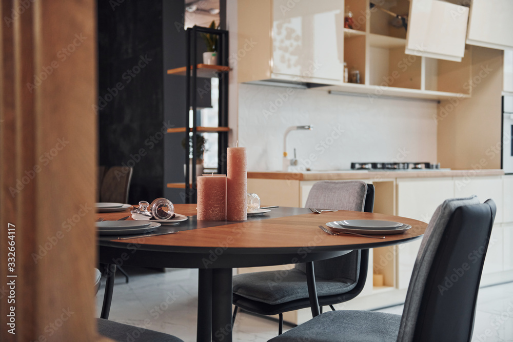 Interior of modern new kitchen with table and candles with plates on it Interior of modern new kitchen with table and candles with plates on it