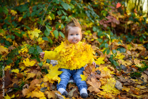 happy little girl laughs and plays outdoors. On the neck there is a necklace of autumn leaves.