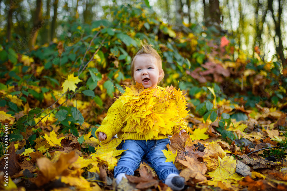 happy little girl laughs and plays outdoors. On the neck there is a necklace of autumn leaves. happy little girl laughs and plays outdoors. On the neck there is a necklace of autumn leaves.