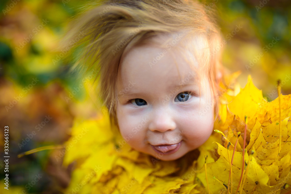 happy little girl laughs and plays outdoors. On the neck there is a necklace of autumn leaves. happy little girl laughs and plays outdoors. On the neck there is a necklace of autumn leaves.