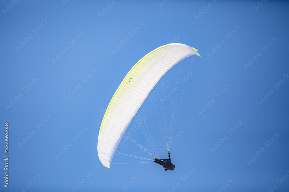 Skydiver with a colorful canopy of a parachute on the background a blue sky