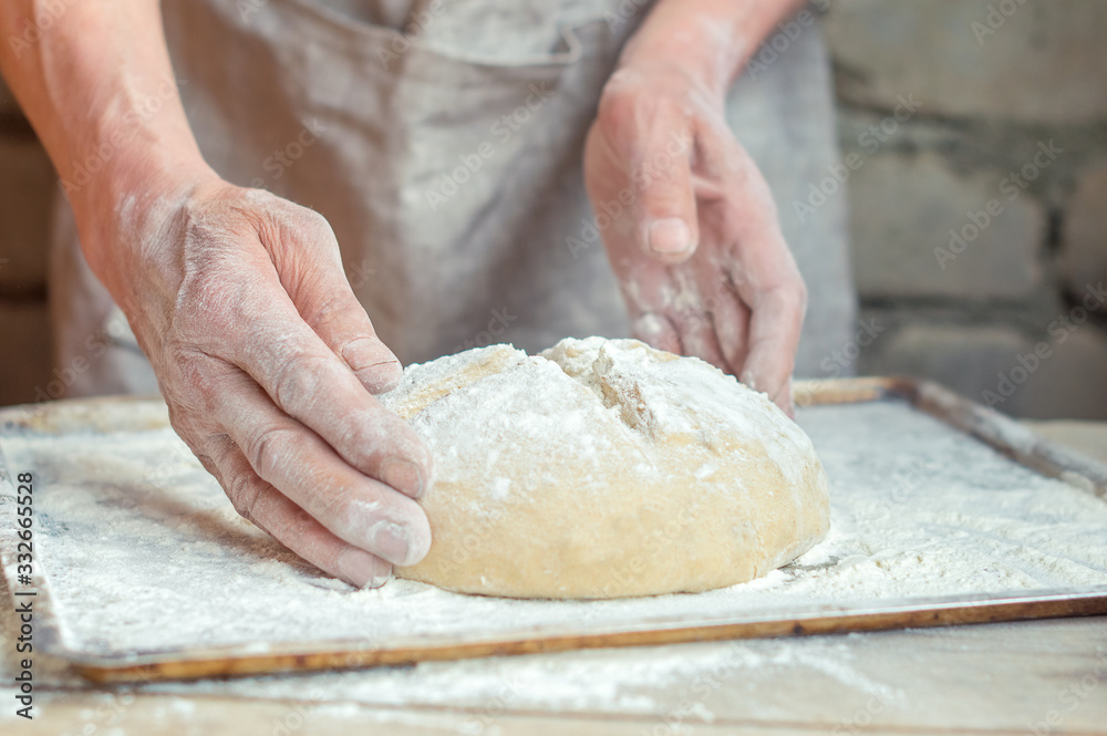 Fototapeta premium Baker's hands and wheat bread before baking. rustic style
