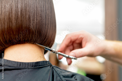 Hairdresser cuts hair tips.