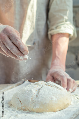 Men's hands knead the dough for homemade bread, the effect of flour, rustic style