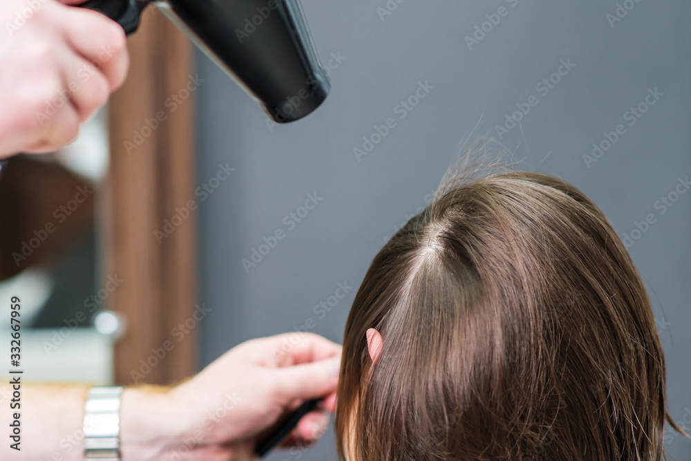 Fototapeta premium Hairstylist dries hair of woman.