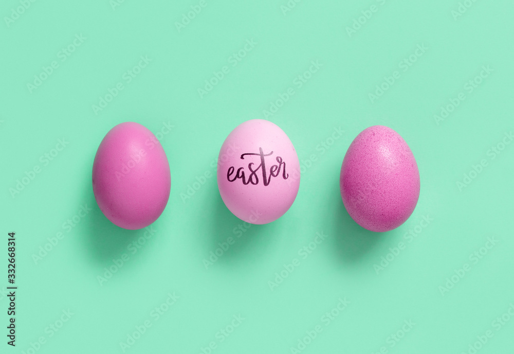 Pink eggs with inscription EASTER over light green background