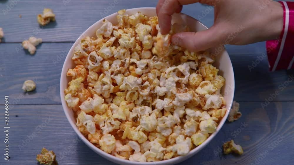 Several hands take popcorn from a large bucket. Exciting fun eating popcorn. Cinema at home. Several hands take popcorn from a large bucket. Exciting fun eating popcorn. Cinema at home.