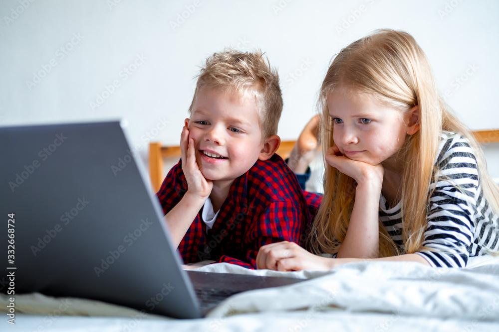 Distance learning online education. Schoolboy and girl studying at home with digital tablet laptop notebook and doing school homework. Sitting on bed with training books Distance learning online education. Schoolboy and girl studying at home with digital tablet laptop notebook and doing school homework. Sitting on bed with training books