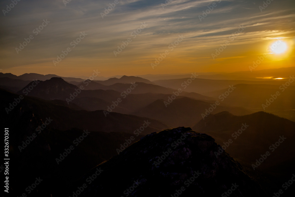 Dark silhouettes of the Carpathian rocky mountains and sunset sky with a large yellow sun