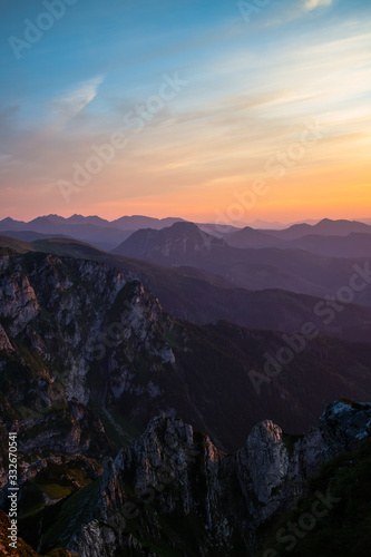 Purple silhouettes of Carpathian rocky mountains and sunset orange-blue sky with clouds