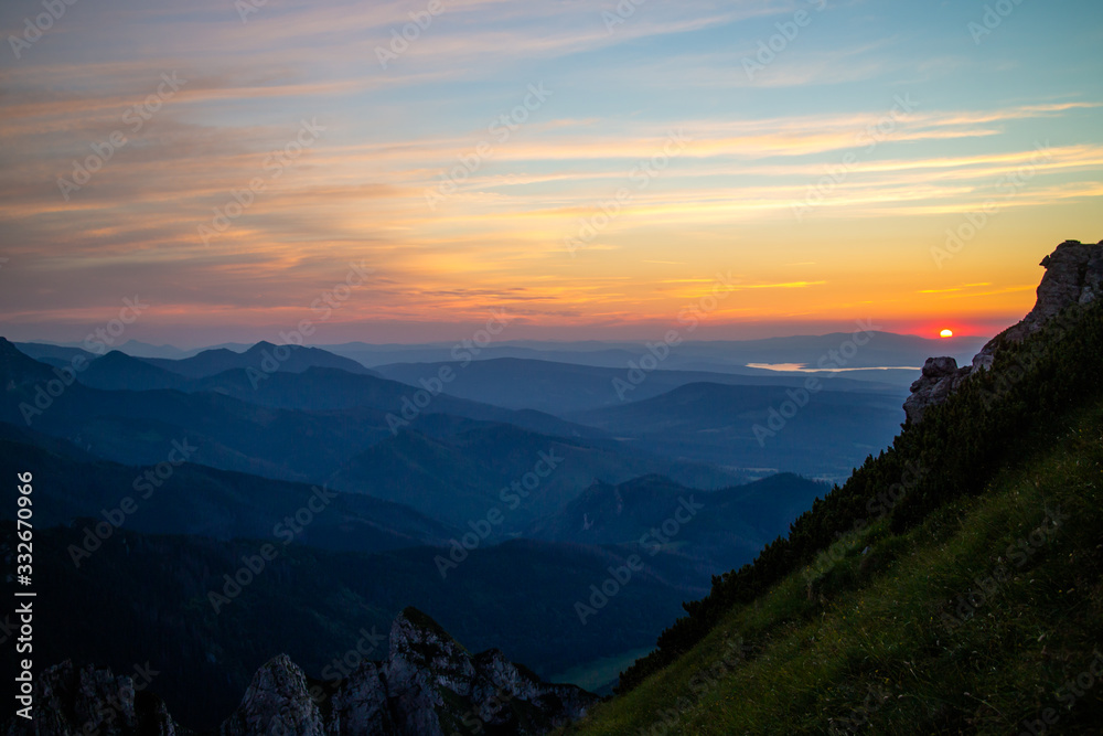 Fototapeta premium Blue silhouettes of Carpathian rocky mountains and sunset orange-blue sky with clouds