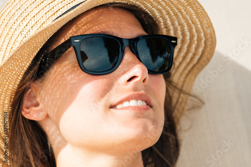 Closeup portrait of a female hides her face from the sun under a straw hat