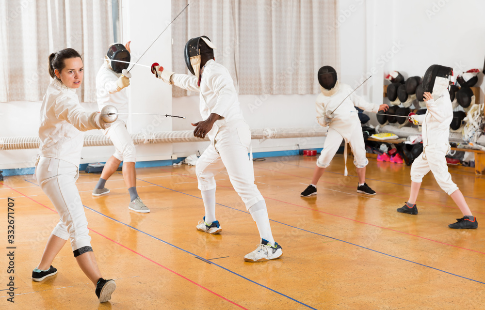Woman wearing fencing uniform practicing with foil