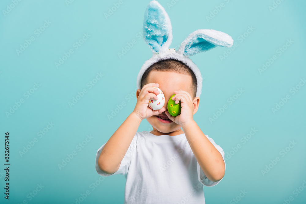 child boy wearing bunny ears and white T-shirt, standing to holds easter eggs instead of eyes