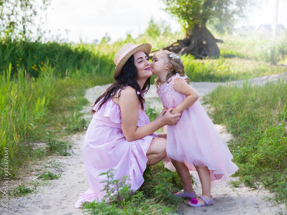 Naklejka premium beautiful mother and daughter outdoors hugging in nature