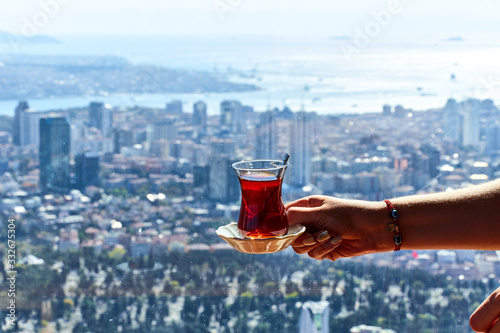 A cup (armud) of traditional Turkish tea in hand on the background of the Istanbul cityscape