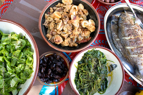 Fried squids calamars fresh fish tsipoura salad greens and olives Sarakosti photo