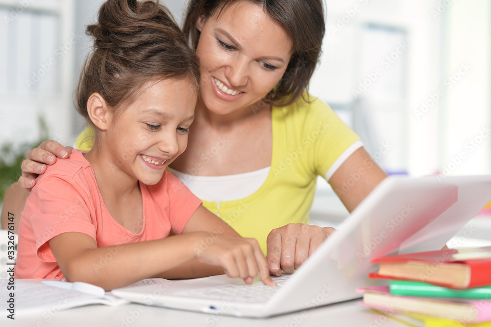 Close up portrait of happy mother and daughter using laptop together Close up portrait of happy mother and daughter using laptop together