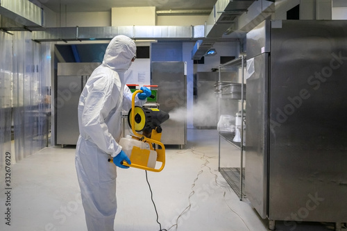 man in protective equipment disinfects with a spray gun surfaces due to coronavirus covid-19 .Virus pandemic. photo