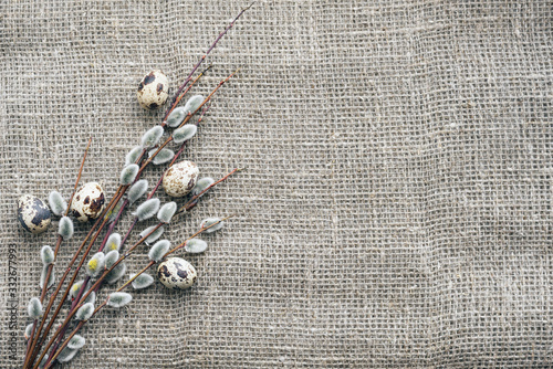Easter card concept with willow branches and quail eggs on canvas background with copy space