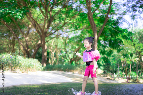 little asian girl wearing inflatable sleeves playing water in nature water on holiday © domonite