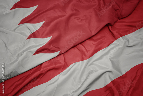 waving colorful flag of austria and national flag of bahrain.