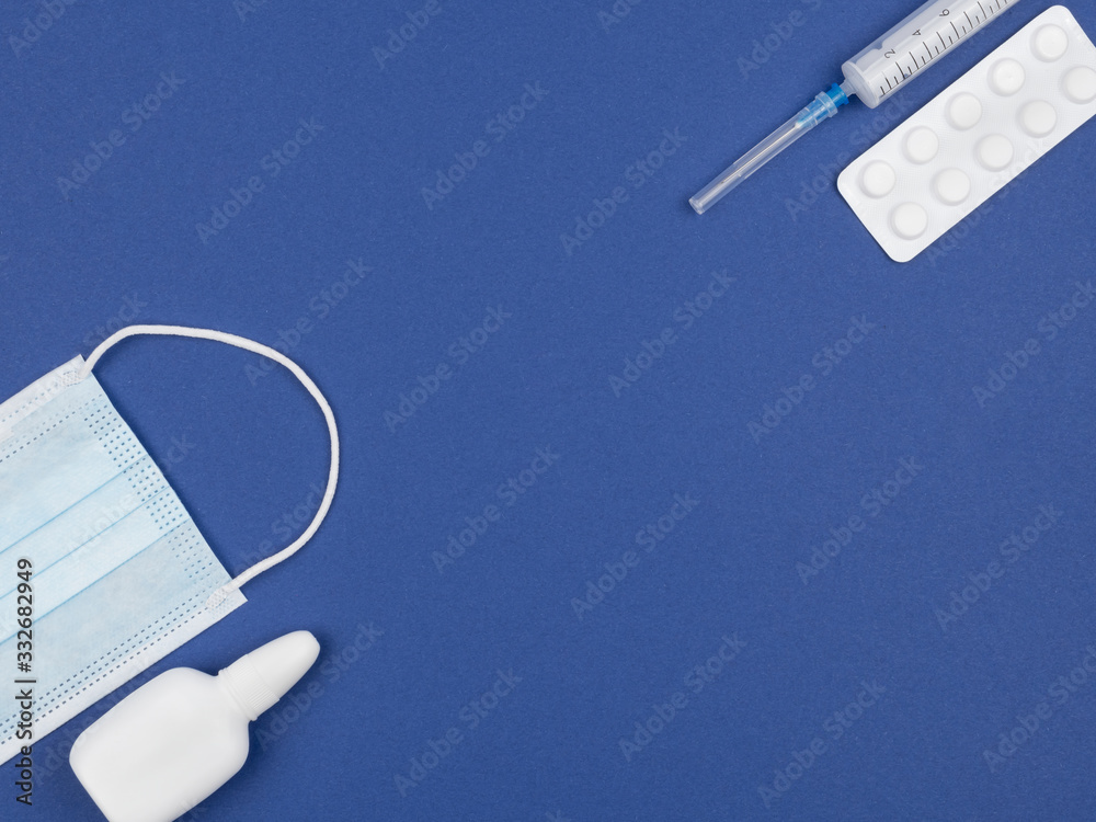 Mask, nasal spray, pills and syringe on a blue background. Mask, nasal spray, pills and syringe on a blue background.