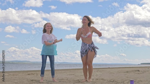 The family dances on the beach. They are not professional dancers. They are fun and they are funny. In video a mother and daughter.