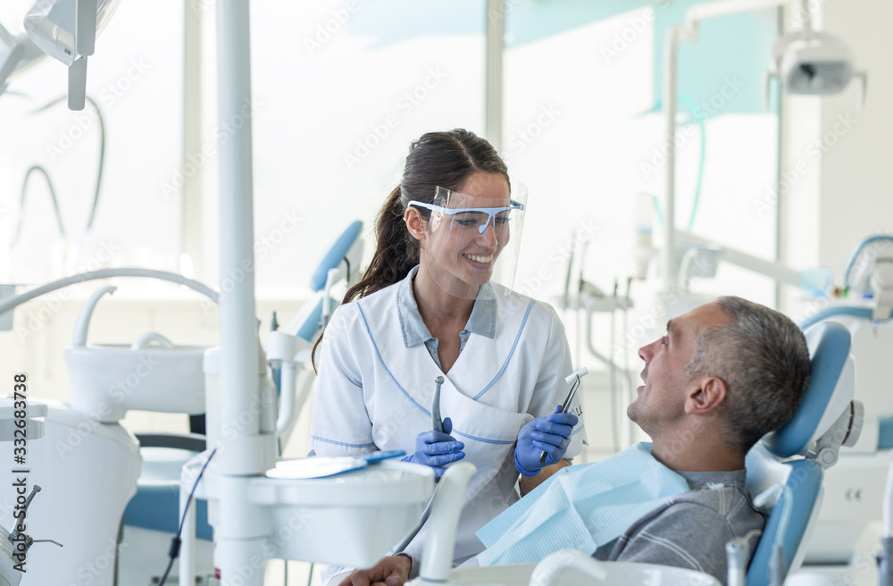 Fototapeta premium Dentist in dental office talking with male patient and preparing for treatment. 
