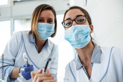 Two female dentist in dental office examining patient teeth.Camera angle from patients perspective. 