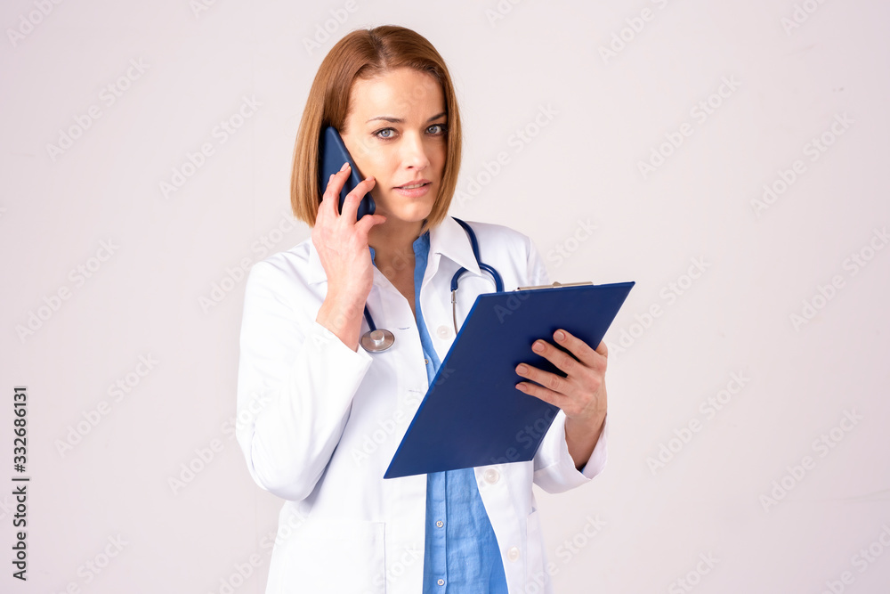 Middle aged female doctor making a call while standing at isolated background Middle aged female doctor making a call while standing at isolated background