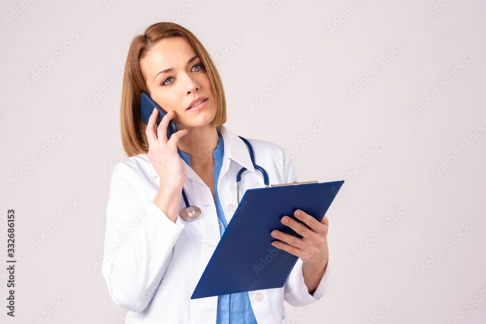 Middle aged female doctor making a call while standing at isolated background Middle aged female doctor making a call while standing at isolated background