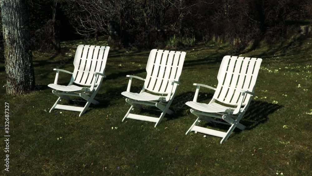 Three white chairs in a garden in spring Three white chairs in a garden in spring