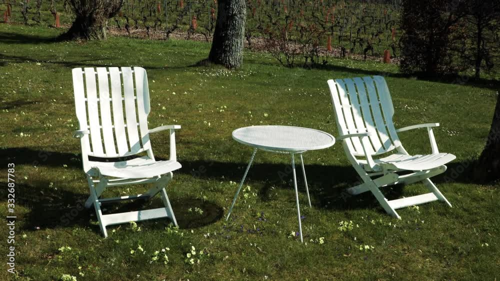 Two white chairs in a garden in spring Two white chairs in a garden in spring