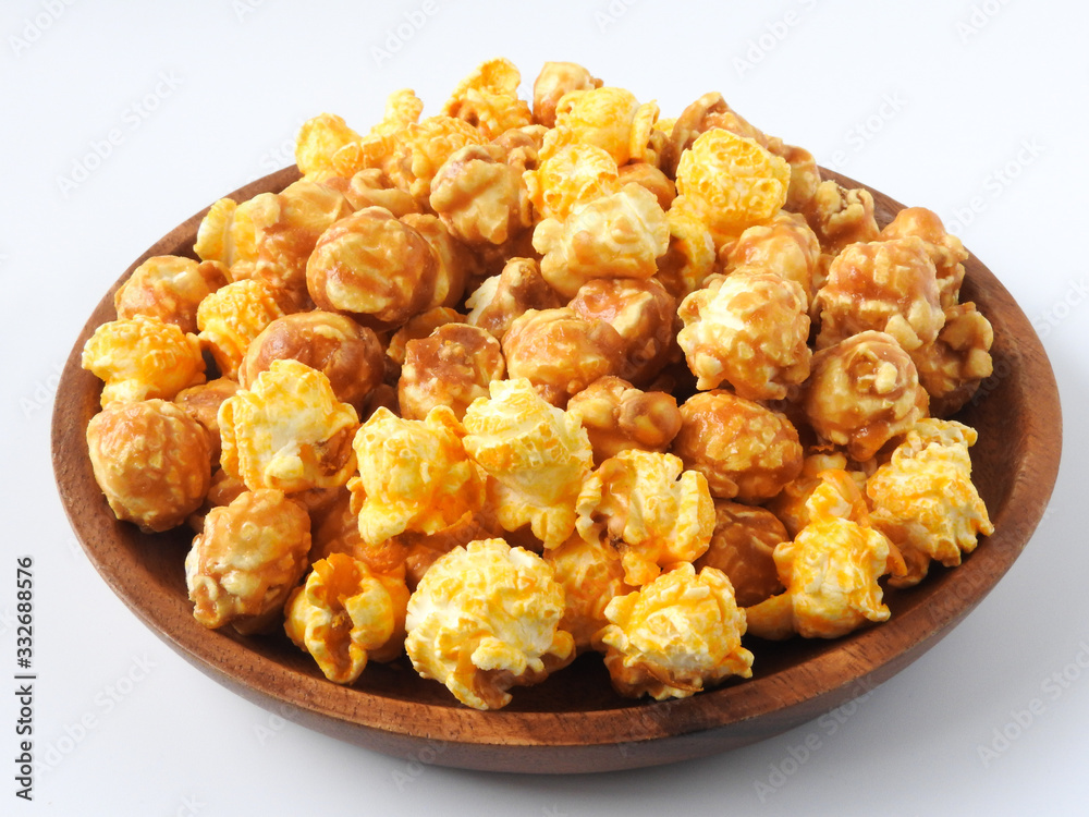 High angle view of delicious popcorn in round wooden plate isolated on white background. Include buttery caramel corn and rich cheddar cheese corn. Food and snack concept. High angle view of delicious popcorn in round wooden plate isolated on white background. Include buttery caramel corn and rich cheddar cheese corn. Food and snack concept.