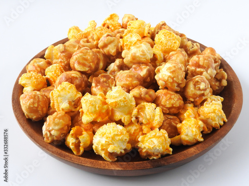 High angle view of delicious popcorn in round wooden plate isolated on white background. Include buttery caramel corn and rich cheddar cheese corn. Food and snack concept.