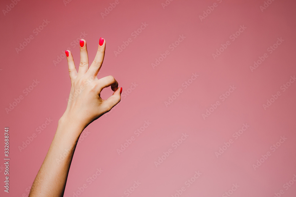 Woman's hands with bright manicure isolated on pink background okay super gesture