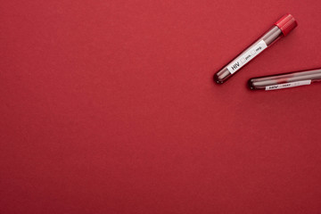 top view of test tubes with blood samples for HIV test on red background