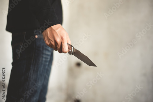 Close up of man holding knife in abandoned house. Terrorist and Robber concept. Police and Soldier. Weapon and armed theme