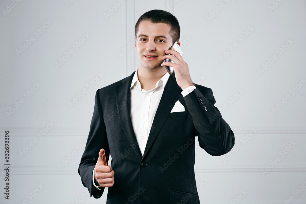 Portrait of a happy handsome businessman entrepreneur talking on phone holding the pen Portrait of a happy handsome businessman entrepreneur talking on phone holding the pen
