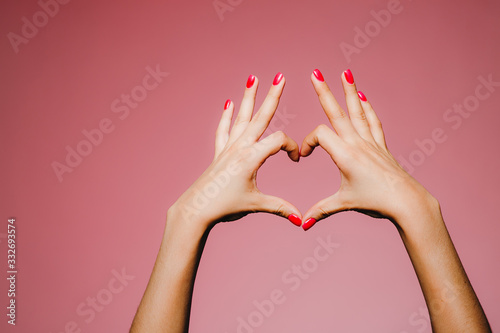 Woman's hands with bright manicure isolated on pink background love sign fingers up photo