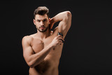 sexy naked man applying deodorant on armpit isolated on black