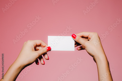 Woman's hands hold blank business card isolated on pink