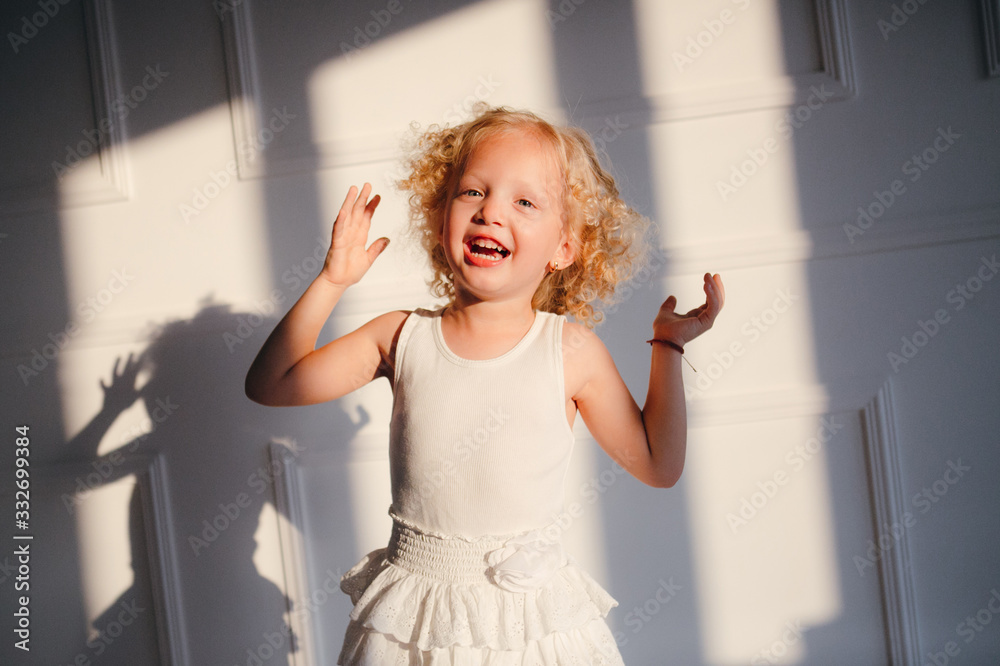 A curly blonde girl in white dress dances, laughs, jumps A curly blonde girl in white dress dances, laughs, jumps