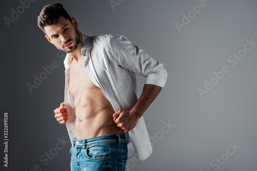 sexy handsome man in white shirt and jeans on grey photo