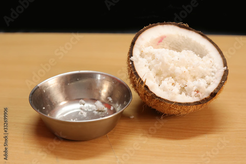 Coconuts with coconut flakes and stainless steel Bowl are isolated on a wooden table on a black background