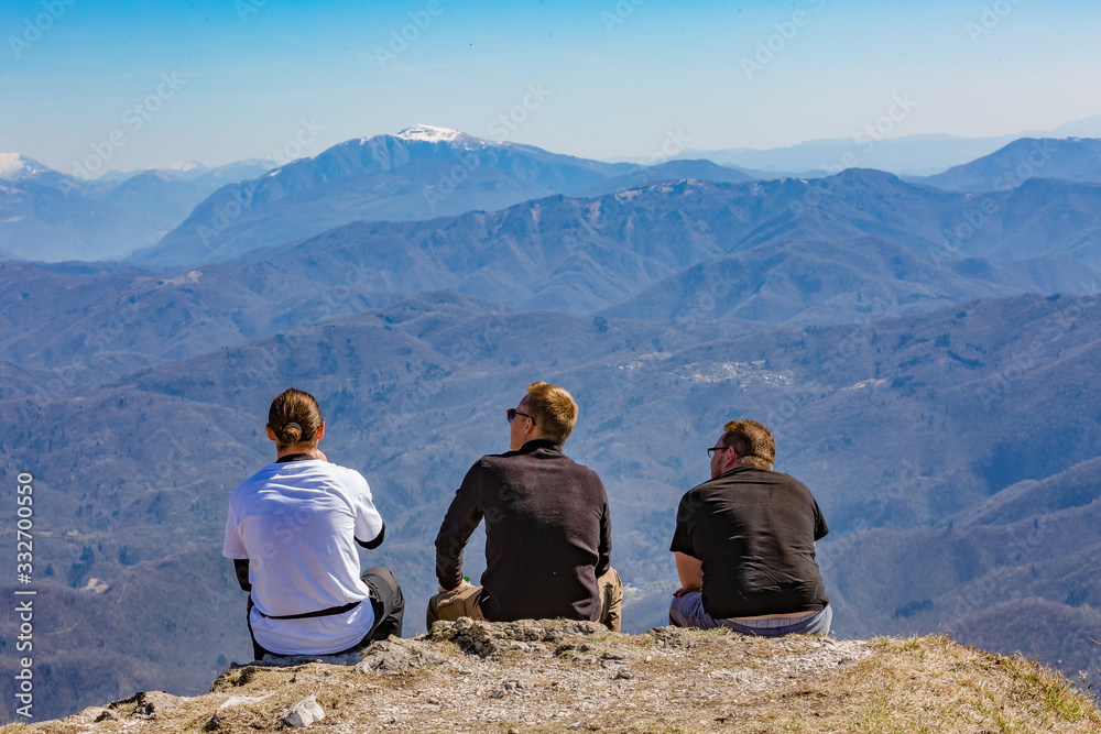 Three heroes. Three men sit on the top of the hill and admire the mountain scenery