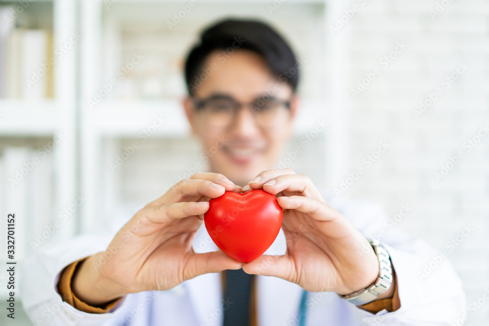 Happy Asian specialist doctor holding the red heart ball on his hands. Concept of health care and wellbeing in modern lifestyle. ECG and pulse diagnosis in hospital. The cardiology medical science. Happy Asian specialist doctor holding the red heart ball on his hands. Concept of health care and wellbeing in modern lifestyle. ECG and pulse diagnosis in hospital. The cardiology medical science.