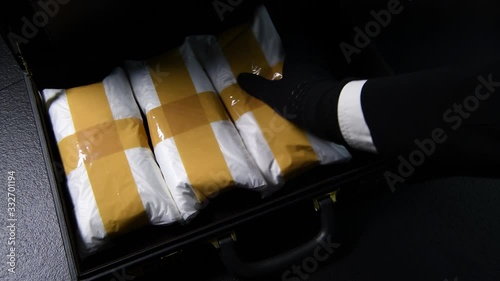 A hand packing narcotic drugs and money in briefcase .